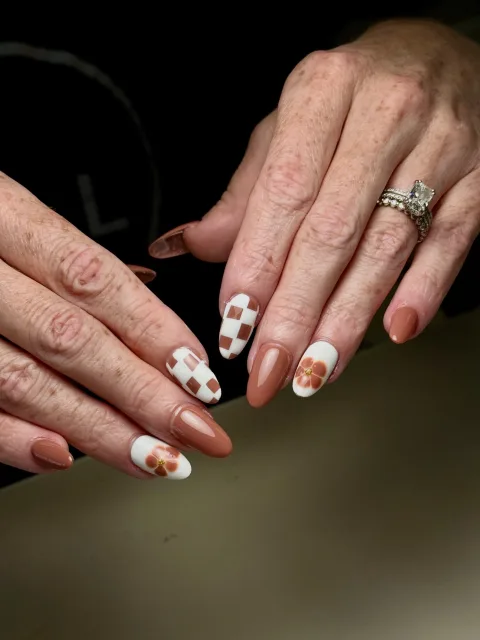 Warm neutral nails with white checks and floral accents