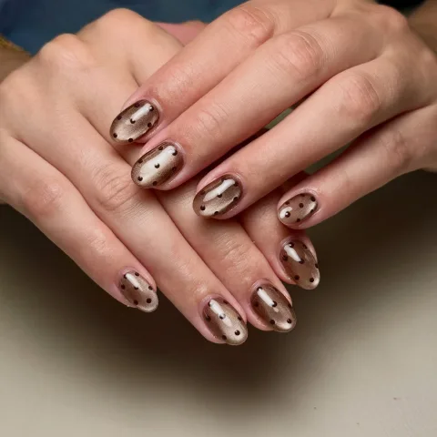 Short rounded taupe shimmer nails with dark polka dots